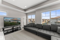 Spacious room with light gray walls, plush carpeting, large windows, and a tray ceiling with recessed lighting - 