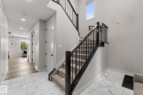 Staircase with dark wood newel posts and railings, black metal spindles, and carpeted treads - 12383 176 Avenue Nw, Edmonton, AB - Indoor Photo Showing Other Room