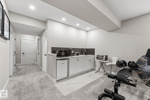 Lower level featuring a built-in kitchenette with a mini-refrigerator, sink, and dark tiled backsplash - 12383 176 Avenue Nw, Edmonton, AB - Indoor Photo Showing Other Room