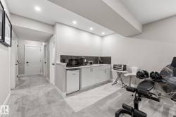 Lower level featuring a built-in kitchenette with a mini-refrigerator, sink, and dark tiled backsplash - 