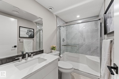 Bathroom featuring a white vanity with an integrated rectangular sink and polished chrome faucet, dark subway tile backsplash, and a large mirror - 12383 176 Avenue Nw, Edmonton, AB - Indoor Photo Showing Bathroom