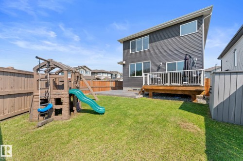 Rear exterior featuring dark gray siding, a wood deck with white railing, and a manicured lawn - 12383 176 Avenue Nw, Edmonton, AB - Outdoor With Deck Patio Veranda