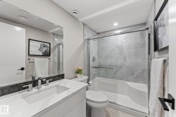 Bathroom featuring a white vanity with an integrated rectangular sink and polished chrome faucet, dark subway tile backsplash, and a large mirror - 