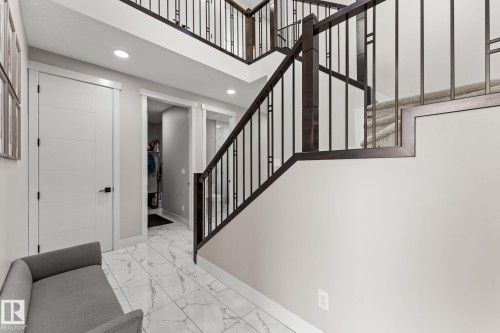 Grand entryway featuring a modern staircase with dark wood and metal railings, light gray walls, white tile flooring with veining, white panel doors, and recessed lighting - 12383 176 Avenue Nw, Edmonton, AB - Indoor Photo Showing Other Room