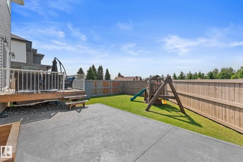 Expansive backyard featuring a concrete patio, wood deck with white railings, and a wooden privacy fence - 12383 176 Avenue Nw, Edmonton, AB - Outdoor