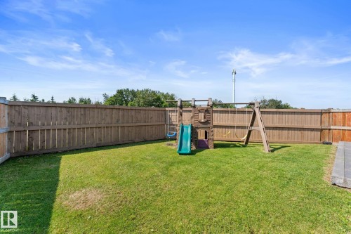 Expansive grassy backyard featuring a full wooden privacy fence and a paver stone patio area - 12383 176 Avenue Nw, Edmonton, AB - Outdoor With Backyard
