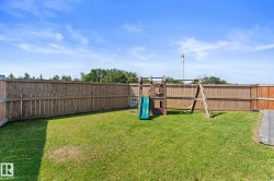 Expansive grassy backyard featuring a full wooden privacy fence and a paver stone patio area - 