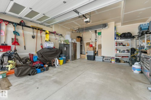 Spacious garage with a concrete floor, overhead garage door featuring translucent panels, and exposed drywall ceiling - 12383 176 Avenue Nw, Edmonton, AB - Indoor Photo Showing Garage