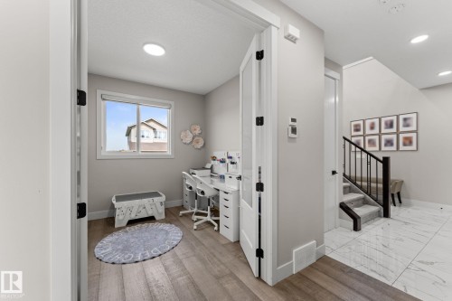 Modern hallway and flex room featuring white shaker-style cabinetry with hardware accents, wood-finish flooring, recessed ceiling lighting, and multiple interior glass doors with black frames - 12383 176 Avenue Nw, Edmonton, AB - Indoor