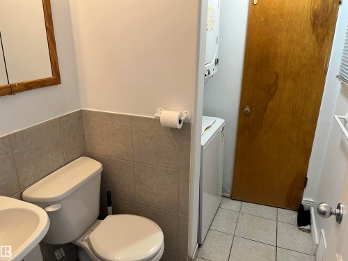 Functional bathroom featuring ceramic tile wainscoting, dual porcelain fixtures, chrome hardware, and ceramic tile flooring - 12011 87 Avenue Nw, Edmonton, AB - Indoor Photo Showing Bathroom