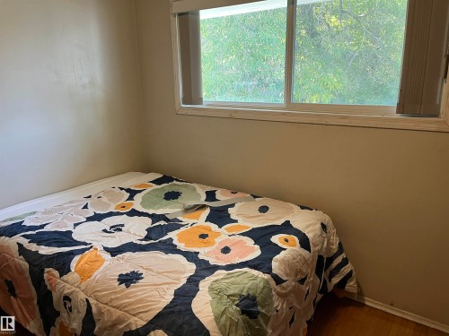 Bedroom with a white-framed window, neutral wall paint, and wood-finish flooring - 12011 87 Avenue Nw, Edmonton, AB - Indoor Photo Showing Bedroom