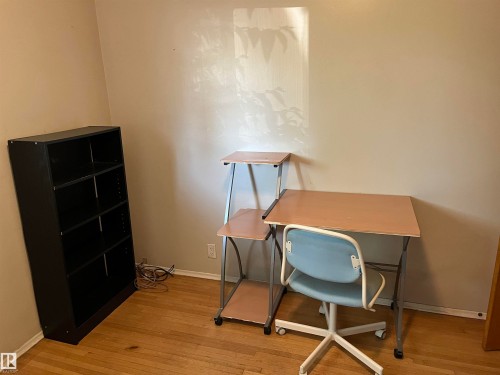 Compact home office featuring hardwood flooring, built-in shelving unit with multiple compartments, ergonomic task seating, and dedicated work surfaces ideal for remote productivity - 12011 87 Avenue Nw, Edmonton, AB - Indoor Photo Showing Office