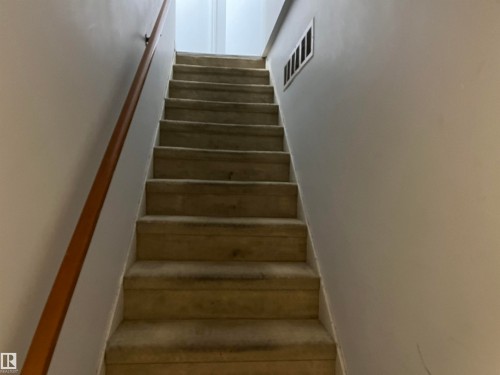 Staircase with wood-finish handrail, neutral wall finishes, and recessed lighting - 12011 87 Avenue Nw, Edmonton, AB - Indoor Photo Showing Other Room