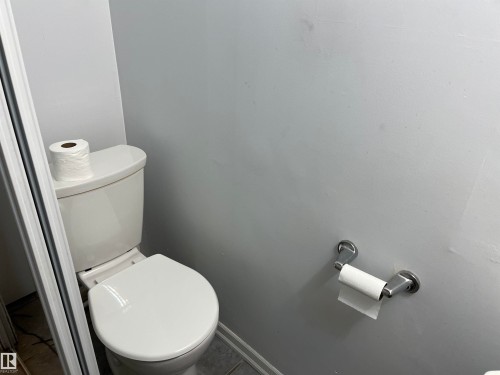 White porcelain toilet with a wall-mounted brushed metal toilet paper holder - 12011 87 Avenue Nw, Edmonton, AB - Indoor Photo Showing Bathroom