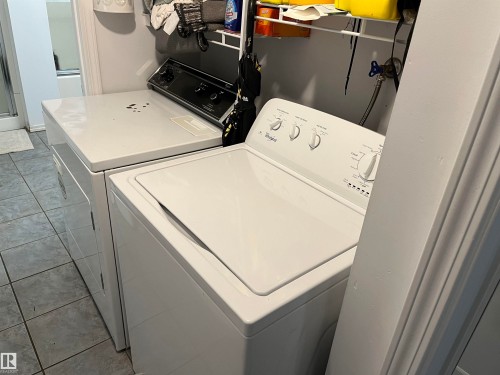 Laundry room featuring side-by-side washer and dryer units with white finish, complemented by white cabinetry and tile flooring - 12011 87 Avenue Nw, Edmonton, AB - Indoor Photo Showing Laundry Room
