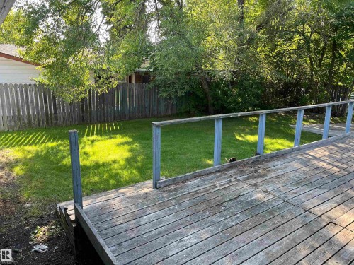 Expansive outdoor deck with wood planking and railing, overlooking a verdant lawn - 12011 87 Avenue Nw, Edmonton, AB - Outdoor