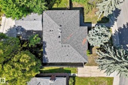 Property featuring a grey shingle roof, established landscaping, and a paved driveway - 
