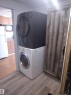 Laundry area featuring a stacked washer and dryer unit, wood-finish flooring, and a barn-style wooden door - 42 Midland Road, Millet, AB  - Indoor Photo Showing Laundry Room 