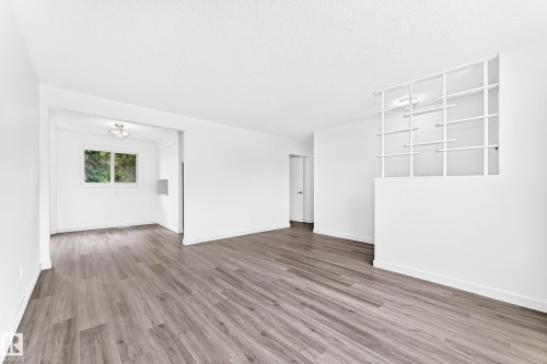 Spacious room featuring wood-finish flooring, white painted walls, and a decorative built-in wall unit - 5519 142 Avenue Nw, Edmonton, AB - Indoor Photo Showing Other Room