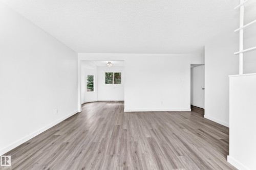 Spacious room featuring wood-finish flooring, white baseboards, and a built-in shelving unit - 5519 142 Avenue Nw, Edmonton, AB - Indoor Photo Showing Other Room