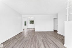 Spacious room featuring wood-finish flooring, white baseboards, and a built-in shelving unit - 