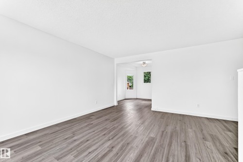 Spacious room featuring wood-finish flooring, crisp white walls, and bright white baseboards - 5519 142 Avenue Nw, Edmonton, AB - Indoor Photo Showing Other Room
