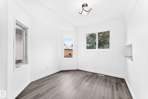 Bright interior space featuring wood-finish flooring, white walls, and multiple windows - 5519 142 Avenue Nw, Edmonton, AB - Indoor Photo Showing Other Room