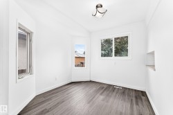 Bright interior space featuring wood-finish flooring, white walls, and multiple windows - 