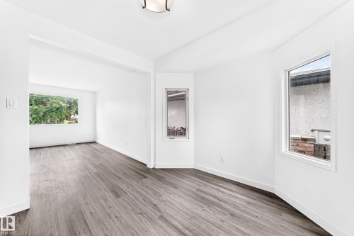 Bright interior space featuring wood-finish flooring, white walls, and multiple windows - 5519 142 Avenue Nw, Edmonton, AB - Indoor Photo Showing Other Room
