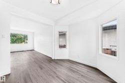 Bright interior space featuring wood-finish flooring, white walls, and multiple windows - 