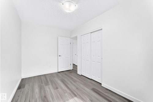 Room featuring wood-finish flooring, white baseboards, a flush-mount ceiling light, and a closet with bifold doors - 5519 142 Avenue Nw, Edmonton, AB - Indoor Photo Showing Other Room