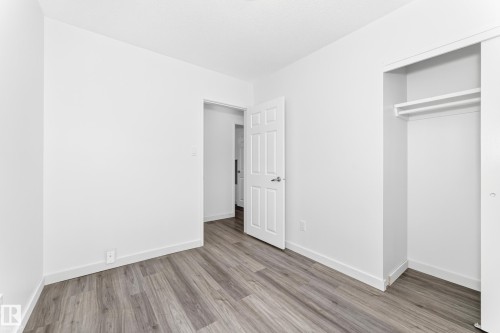 Neutral white walls and wood-finish flooring define this interior space - 5519 142 Avenue Nw, Edmonton, AB - Indoor Photo Showing Other Room