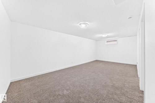 Spacious room featuring neutral carpeting, white walls, two flush-mount ceiling lights, a small window, and white baseboards - 5519 142 Avenue Nw, Edmonton, AB - Indoor Photo Showing Other Room