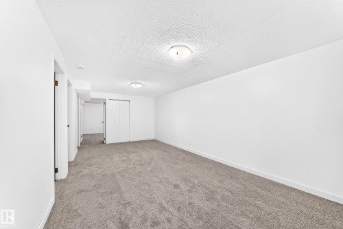 Spacious room featuring neutral carpeting, white walls, and bright overhead lighting - 5519 142 Avenue Nw, Edmonton, AB - Indoor Photo Showing Other Room