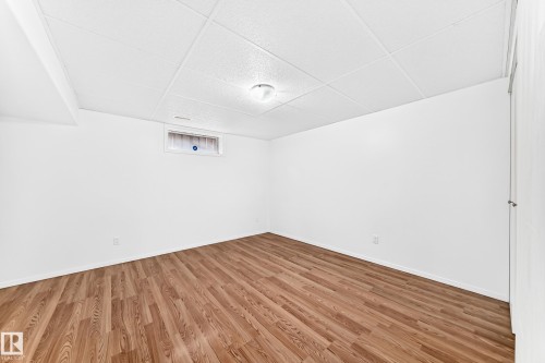 Open room featuring wood-finish flooring, white walls, and a white grid ceiling with recessed lighting - 5519 142 Avenue Nw, Edmonton, AB - Indoor Photo Showing Other Room