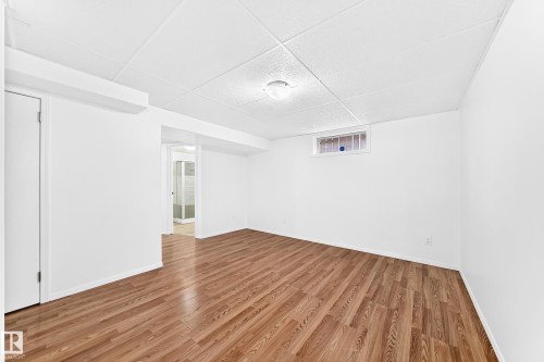 Spacious room featuring wood-finish flooring, white walls, and a drop ceiling with recessed lighting - 5519 142 Avenue Nw, Edmonton, AB - Indoor Photo Showing Other Room