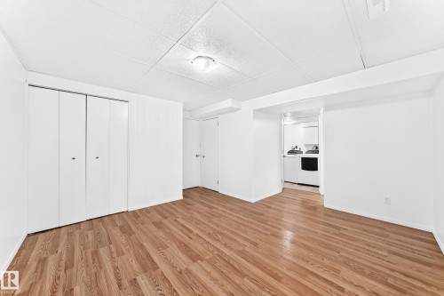 Spacious room featuring wood-finish flooring, white walls, and a drop ceiling - 5519 142 Avenue Nw, Edmonton, AB - Indoor Photo Showing Other Room
