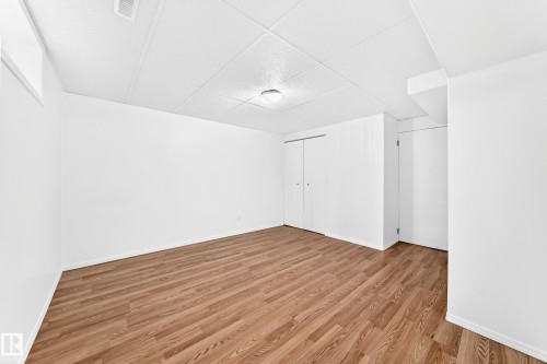 Expansive room featuring wood-finish flooring, white painted walls, and a drop ceiling - 5519 142 Avenue Nw, Edmonton, AB - Indoor Photo Showing Other Room