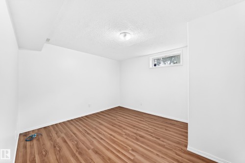 Bright interior room featuring wood-finish flooring, white painted walls, and a white ceiling with a flush-mount light fixture - 5519 142 Avenue Nw, Edmonton, AB - Indoor Photo Showing Other Room