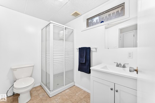 Bathroom with a glass-enclosed shower, white vanity with integrated sink, chrome faucet, white toilet, and tiled flooring - 5519 142 Avenue Nw, Edmonton, AB - Indoor Photo Showing Bathroom