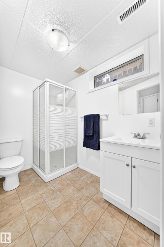 Bathroom featuring a corner glass-enclosed shower, white vanity with integrated sink, and a toilet - 5519 142 Avenue Nw, Edmonton, AB - Indoor Photo Showing Bathroom