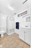 Bathroom featuring a corner glass-enclosed shower, white vanity with integrated sink, and a toilet - 