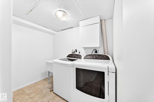 Dedicated laundry area featuring a utility sink, wall-mounted cabinetry, and tile flooring - 5519 142 Avenue Nw, Edmonton, AB - Indoor Photo Showing Laundry Room