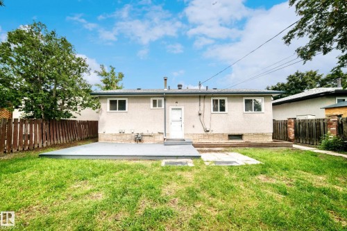 Rear exterior of a stucco home with multiple windows and a central entry door - 5519 142 Avenue Nw, Edmonton, AB - Outdoor With Backyard