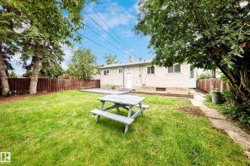 Expansive backyard featuring a manicured lawn, established trees, private fencing, concrete patio area, and stone pathway - 5519 142 Avenue Nw, Edmonton, AB - Outdoor With Backyard