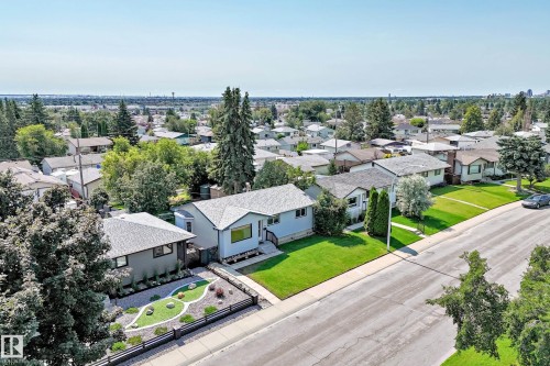 Grey-sided bungalow featuring a dark shingle roof, front landscaping with decorative stones, and a black metal fence - 5519 142 Avenue Nw, Edmonton, AB - Outdoor With View