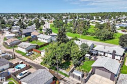 Aerial perspective showcasing a residential neighborhood with detached homes, mature trees, and green spaces - 
