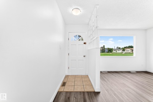 Entryway featuring a white paneled door with an arched glass insert, light-toned square tile flooring, and overhead flush-mount lighting - 5519 142 Avenue Nw, Edmonton, AB - Indoor Photo Showing Other Room