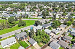 Aerial view showcasing a residential area with single-story homes, mature trees, and paved roads - 