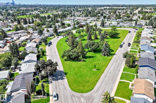 Expansive green space featuring mature trees, surrounded by residential properties and paved roadways - 5519 142 Avenue Nw, Edmonton, AB - Outdoor With View
